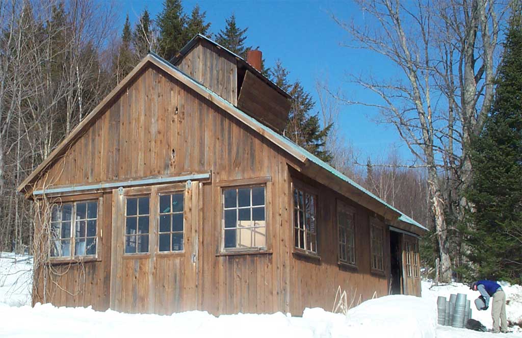 Wooden sugar house in the snow for Massachusetts maple syrup visits.