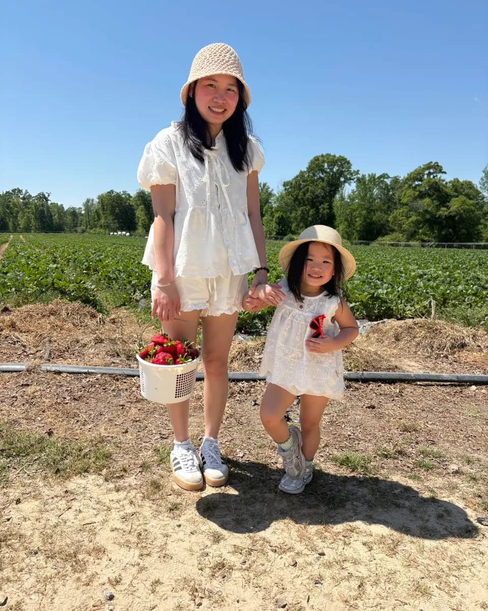 Family strawberry picking with a basket of fresh berries in New Hampshire.