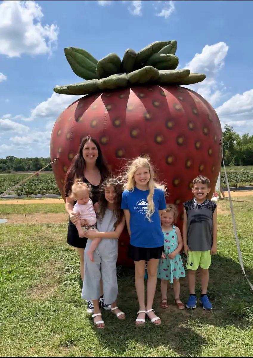 Family photo at a strawberry farm landmark for Maine strawberry picking season.